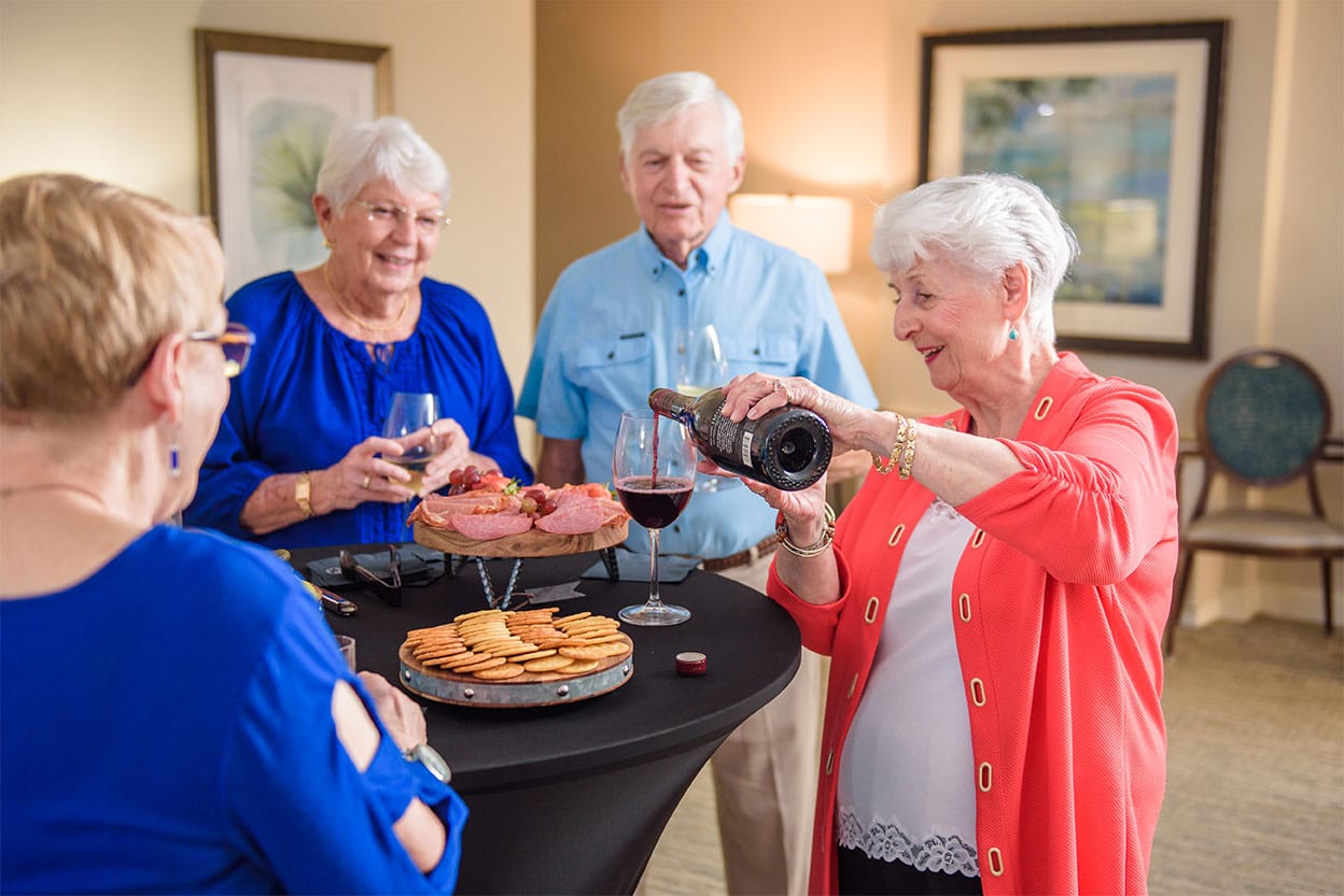 Senior woman pouring wine with friends