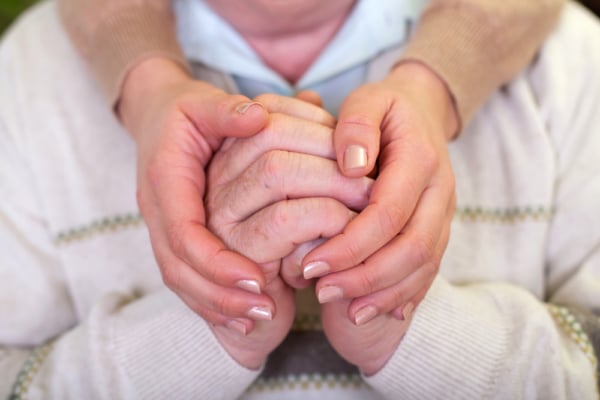 A man and a woman holding hands, showcasing the compassion of Alzheimer's care.