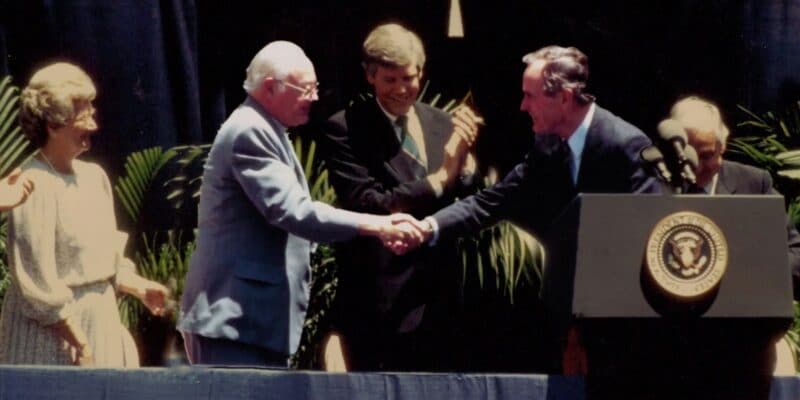 President john f kennedy shakes hands with a group of people.