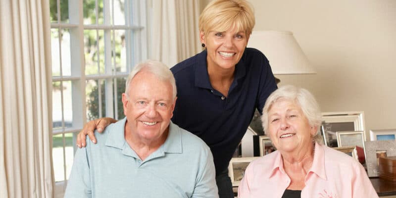 A senior man and a woman are posing for a photo in a living room.