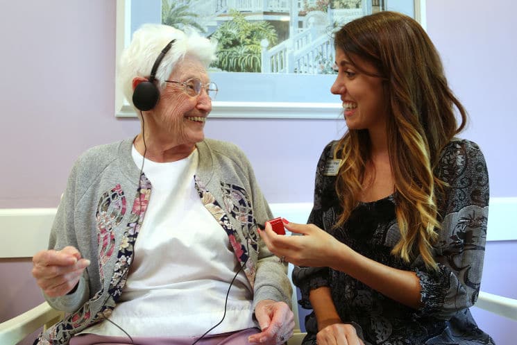 A woman is talking to an elderly woman in a nursing home.