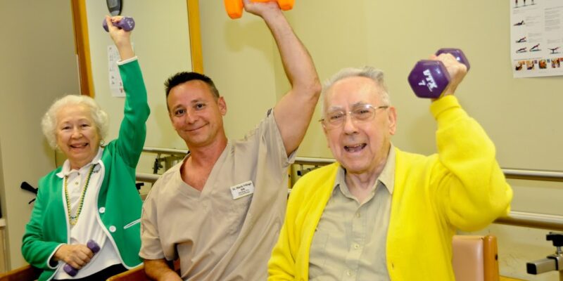 A group of elderly people lifting dumbbells in a gym.