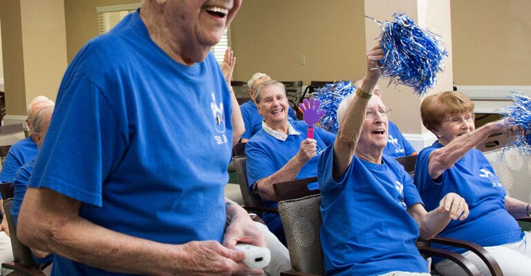 A group of older men in blue shirts and pom poms.