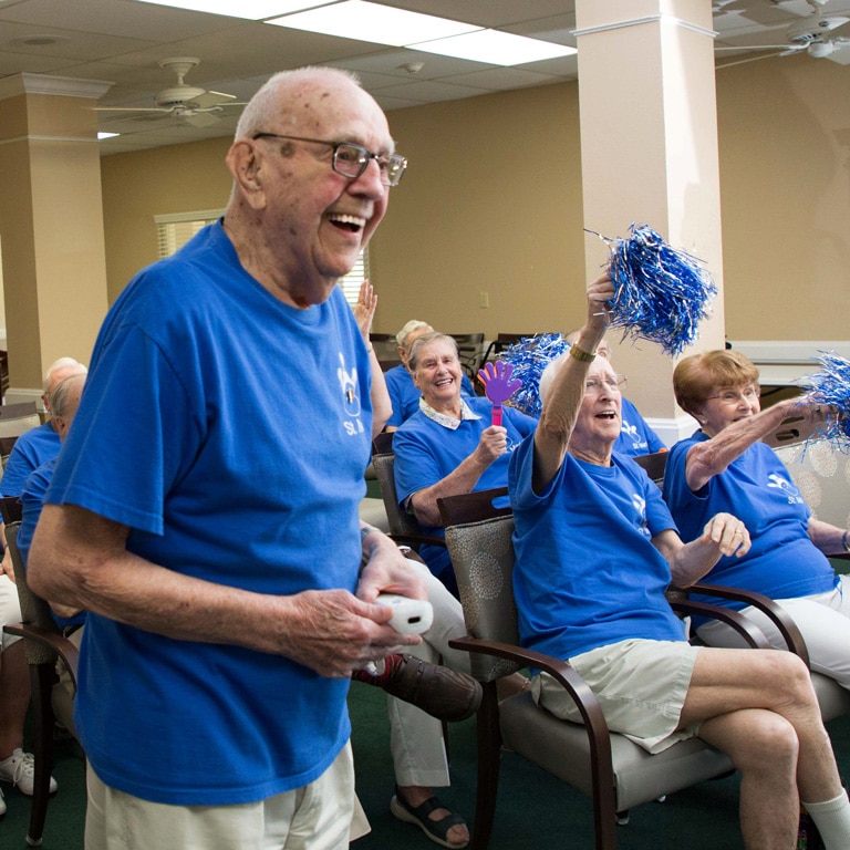 A group of older men in blue shirts and pom poms.