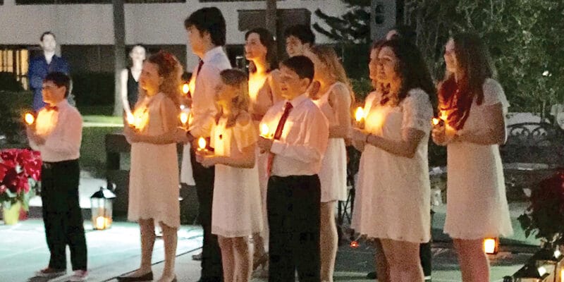 A group of people holding candles in front of a building.