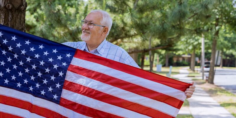 An older man proudly holding an American flag while benefiting from VA support for senior living.