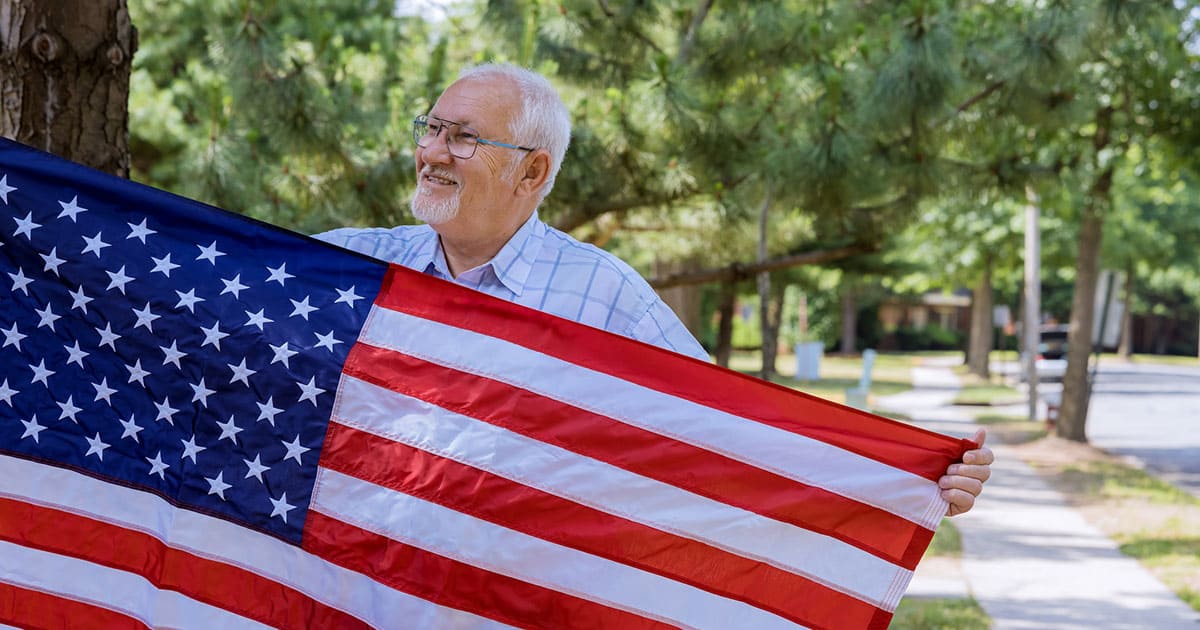 An older man proudly holding an American flag while benefiting from VA support for senior living.