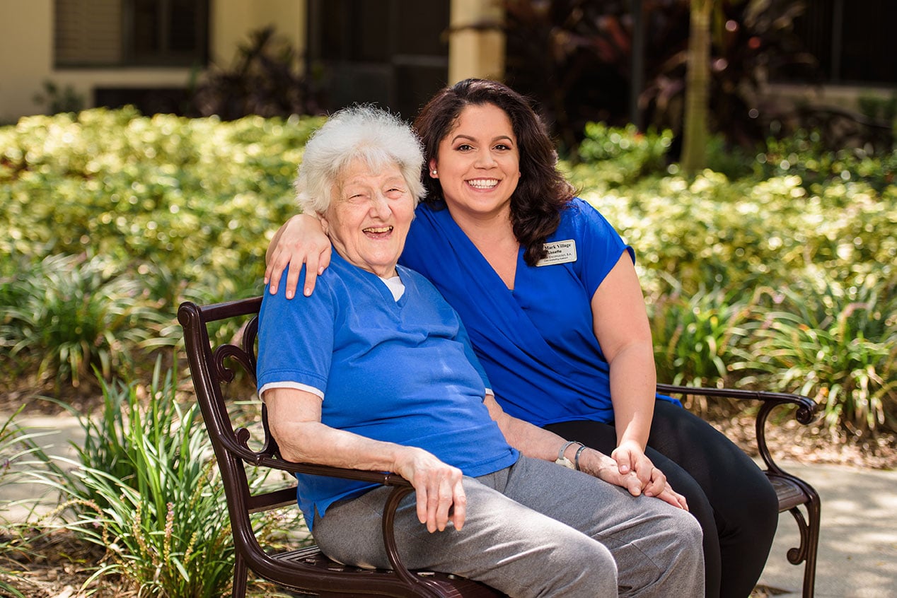 Senior woman with caregiver on a bench outside