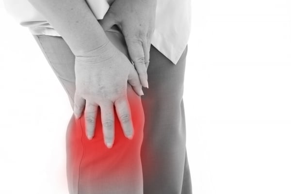 A woman is holding her knee with pain due to arthritis.