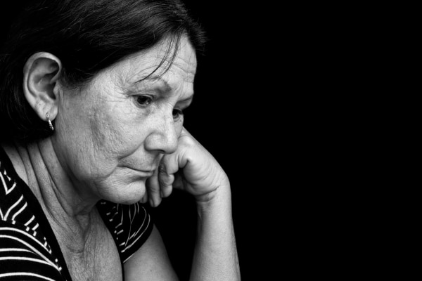 A black and white photo of a pensive woman with her hand on her chin, keeping emotions under control.