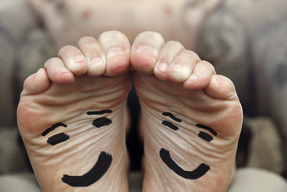 A person's feet with a smiley face drawn on them.