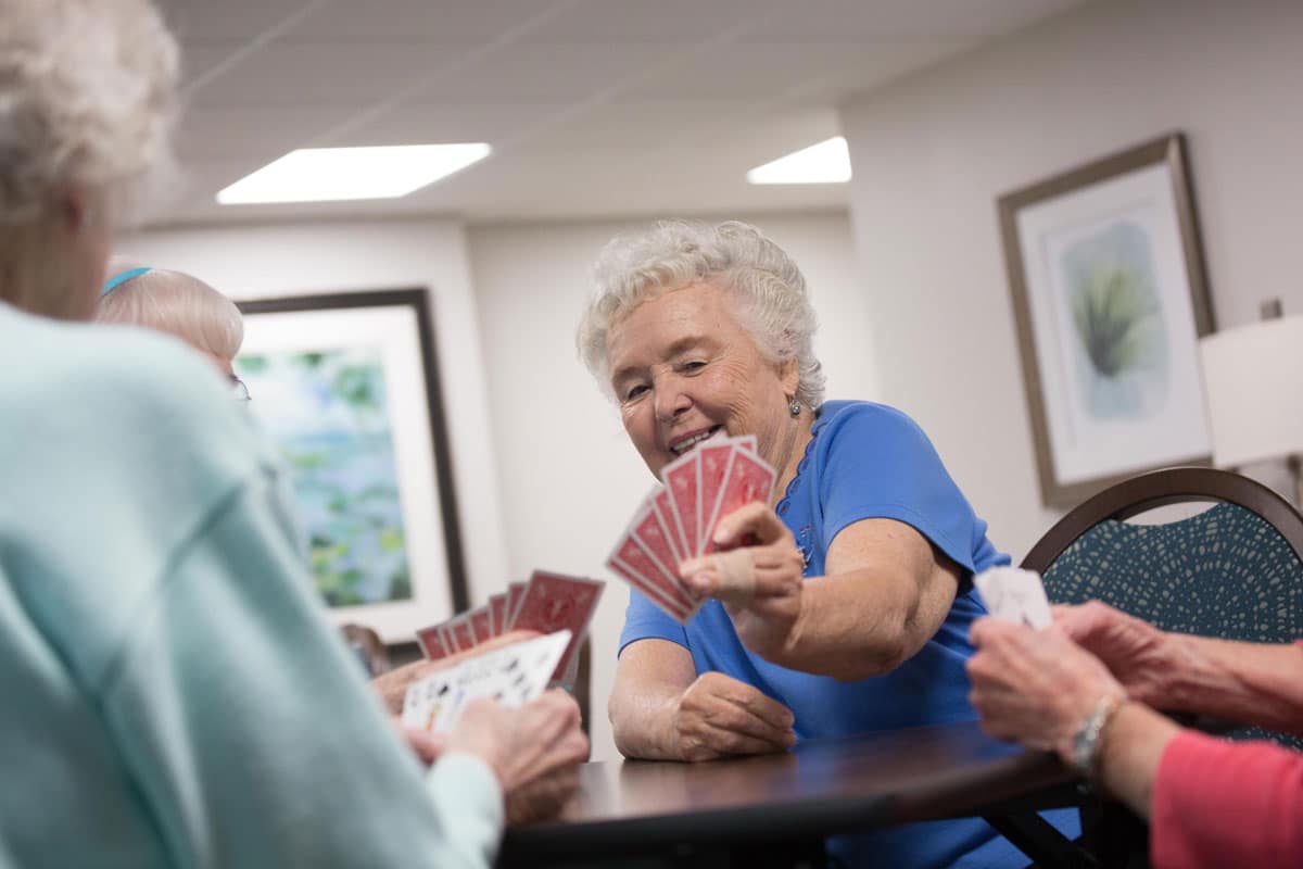 A group of elderly women playing cards at a table.