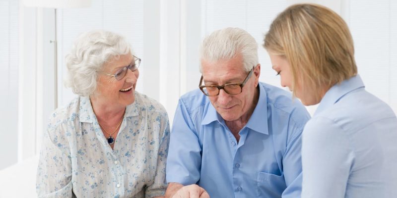 A group of elderly people learning to budget for senior living while looking at a computer.