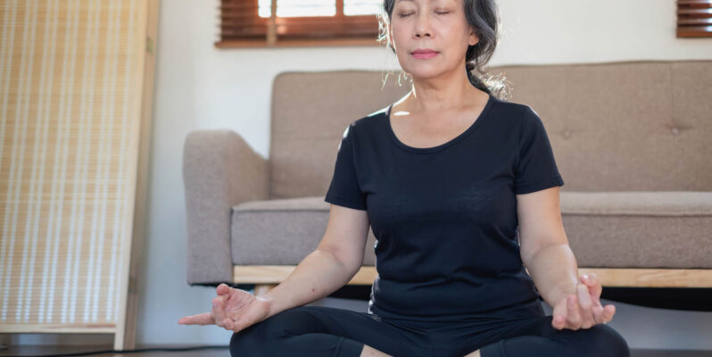 Meditation can relieve anxiety, pain, and depression, and all without the side effects of a medication. Here’s a beginner’s guide for seniors. Woman sitting with legs crossed meditating