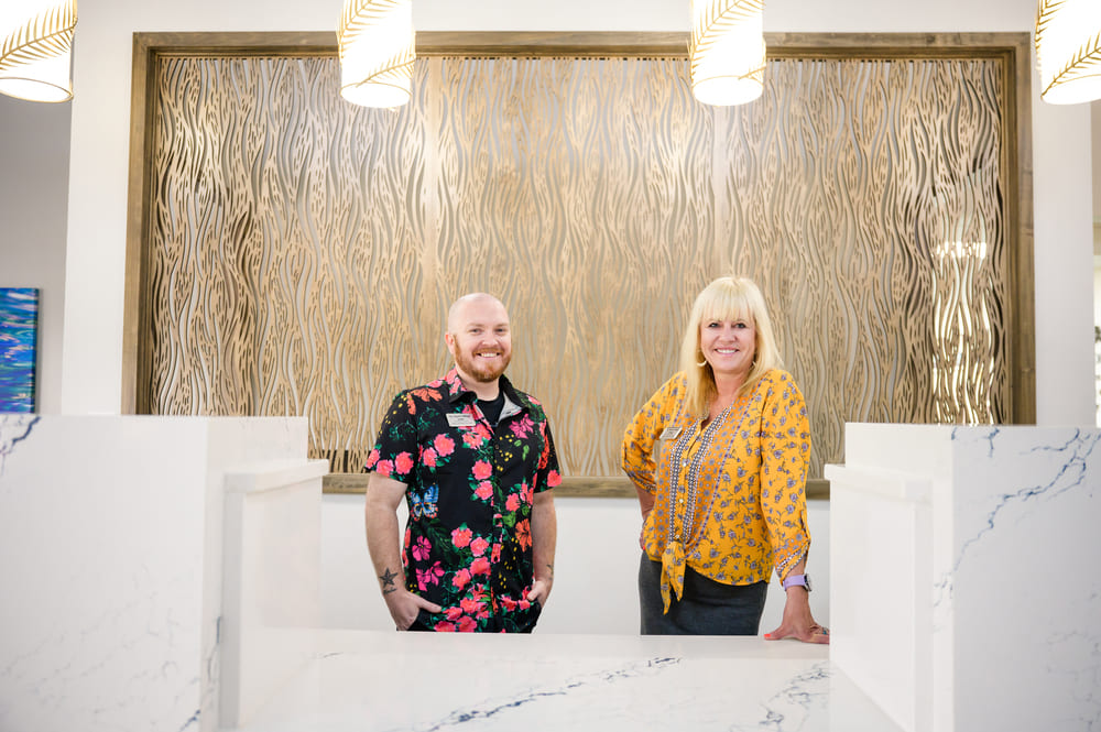 Two people standing in front of the St Mark Village reception desk.