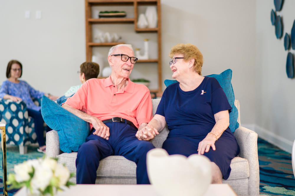 An older couple enjoying the St Mark Village lifestyle, sitting comfortably on a couch in a beautifully decorated living room.