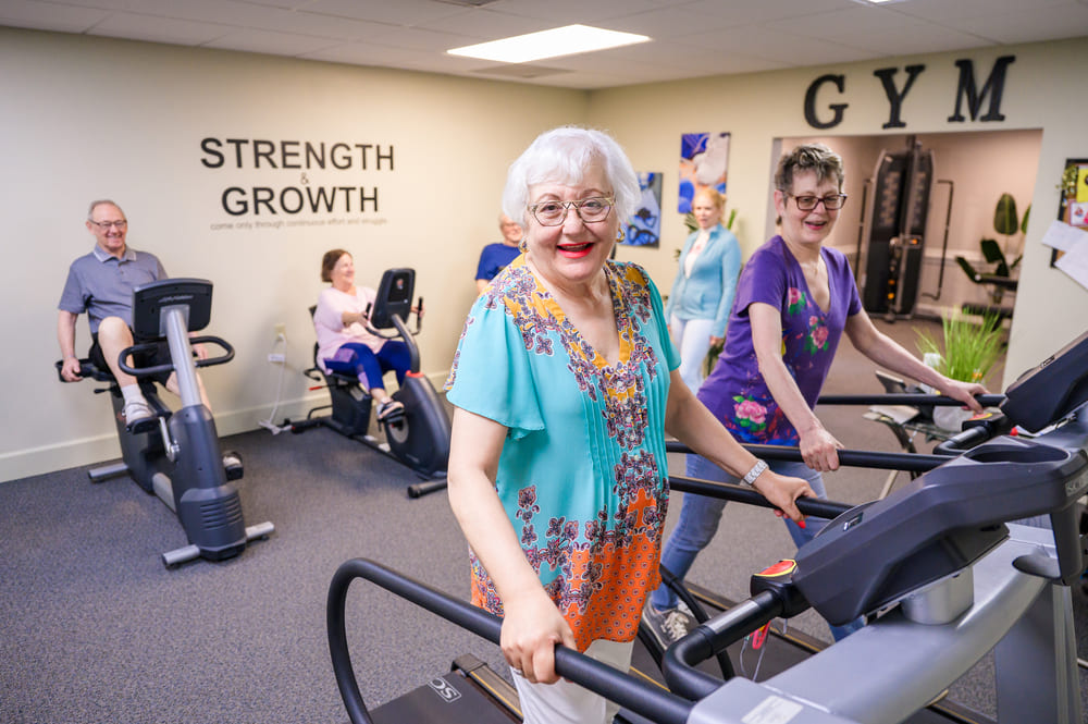 A woman is engaging in a St Mark Village Lifestyle as she rides a stationary bike in a gym.
