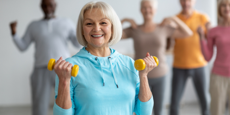 Senior woman in an aerobics class lifting weights.