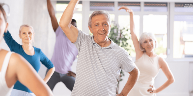 A group of older adults engaged in yoga, a form of movement beneficial for seniors as it promotes flexibility and relaxation in a dedicated space for care options.