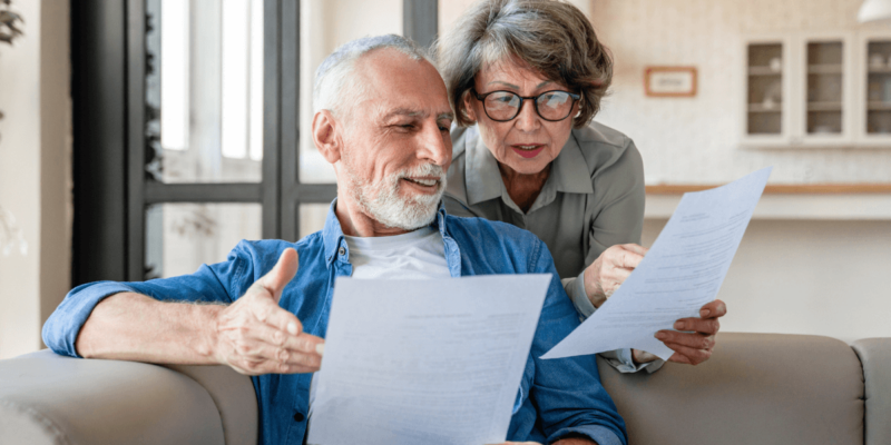 Elder man and woman in the living area on sofa comparing the costs of senior living