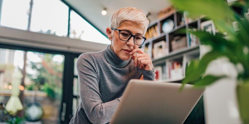 Woman at a computer desk reviewing when it's right for senior living for solo agers.