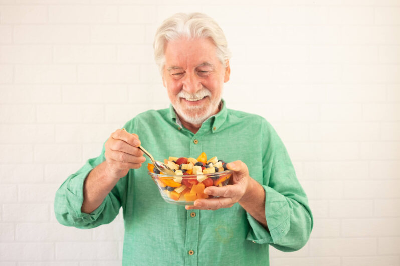 Why Good Nutrition Is So Important for Older Adults, and What It Might Mean When They Overlook Their Own Diet Smiling senior bearded man holding bowl of fresh seasonal fruit ready to eat. Breakfast or lunch, eat healthy and dietary