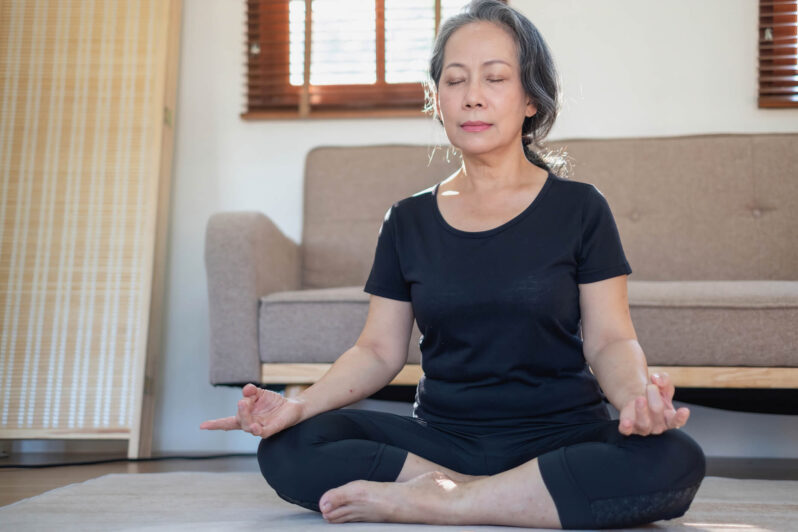 Meditation can relieve anxiety, pain, and depression, and all without the side effects of a medication. Here’s a beginner’s guide for seniors. Woman sitting with legs crossed meditating