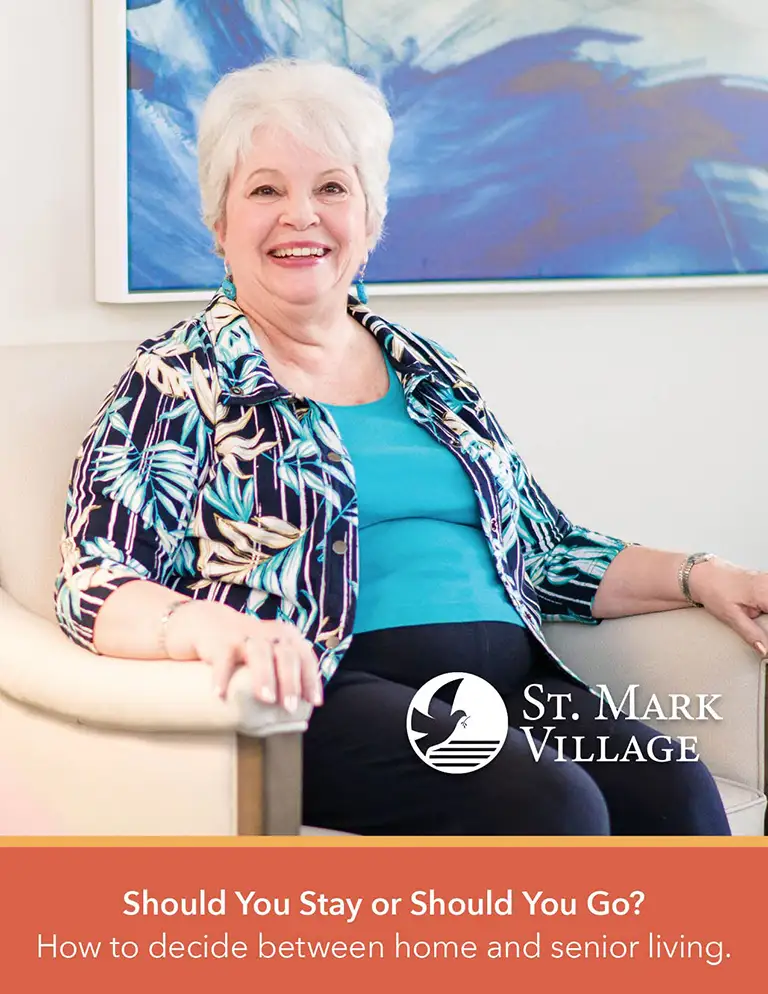Older woman with short white hair sits and smiles in an armchair, with the St. Mark Village logo and text about choosing between home and senior living displayed at the bottom.