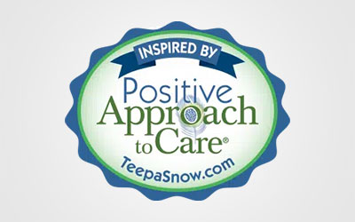 A blue and green badge reads "Inspired by Positive Approach to Care, TeepaSnow.com" on a white background, highlighting St. Mark Village's commitment to positive senior living.